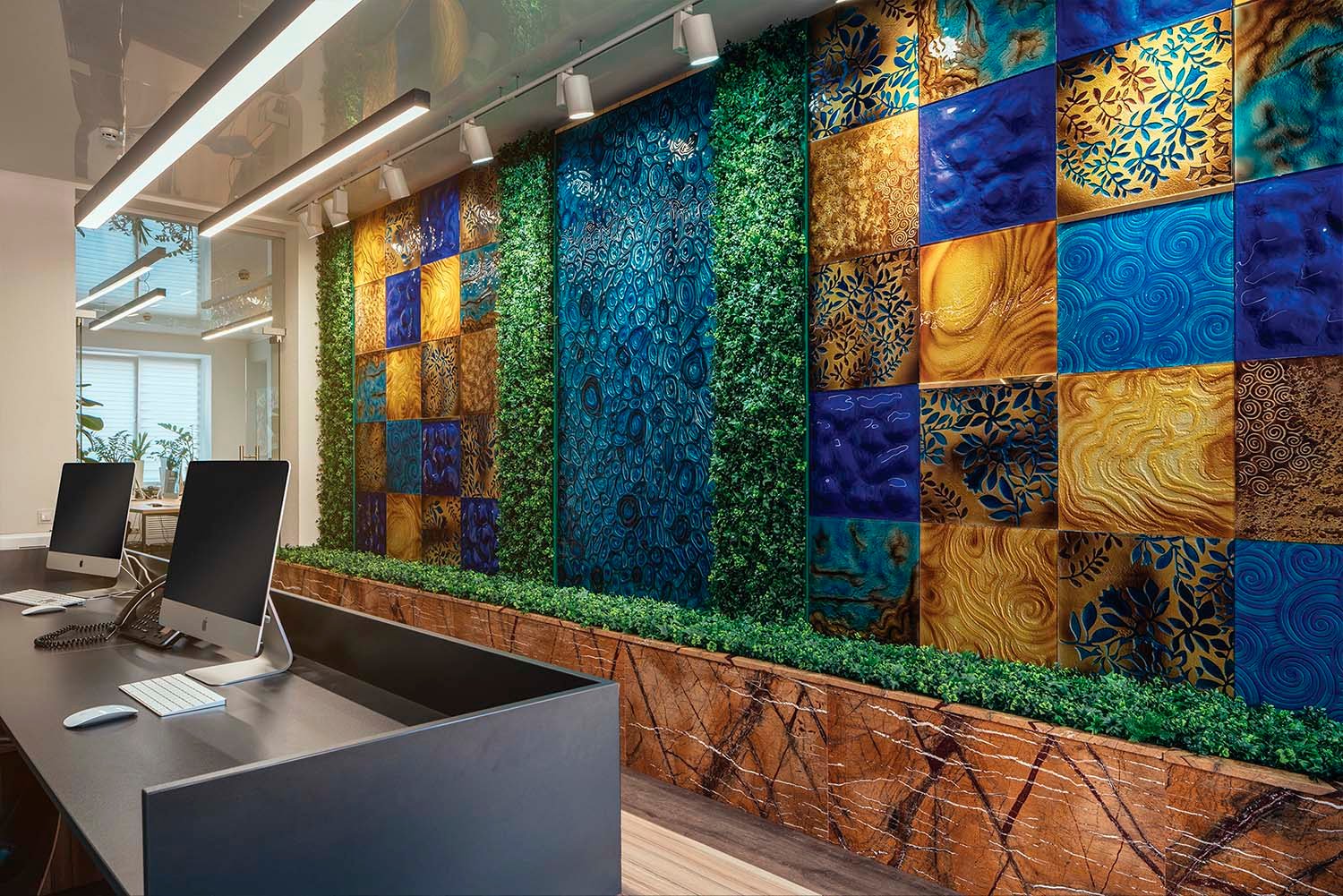 Decorative art wall at SKYFORM STUDIO with colorful textured panels in blue and gold tones, combined with vertical greenery.