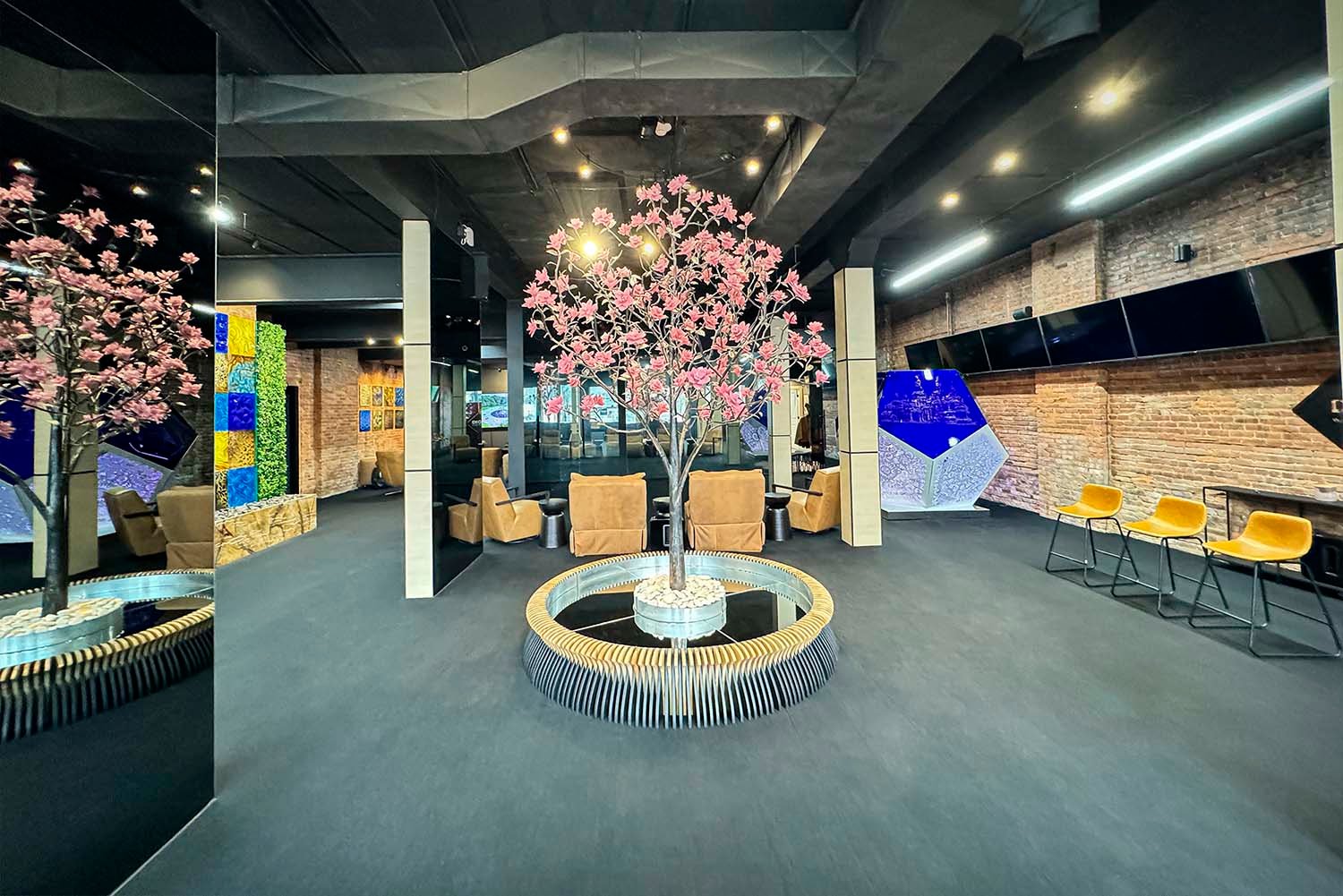 Showroom of SKYFORM STUDIO with central decorative tree installation, lounge seating area, and artistic walls with greenery and panels.