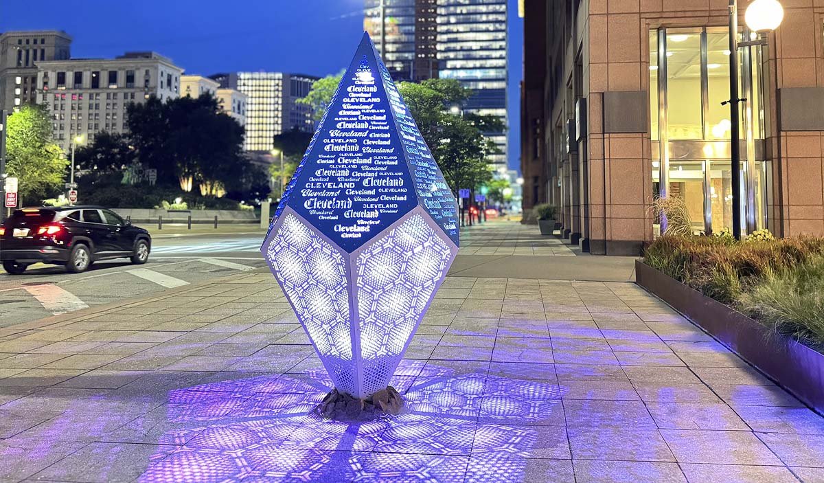 Public art in the form of a crystal with the word "Cleveland" on a city street at night