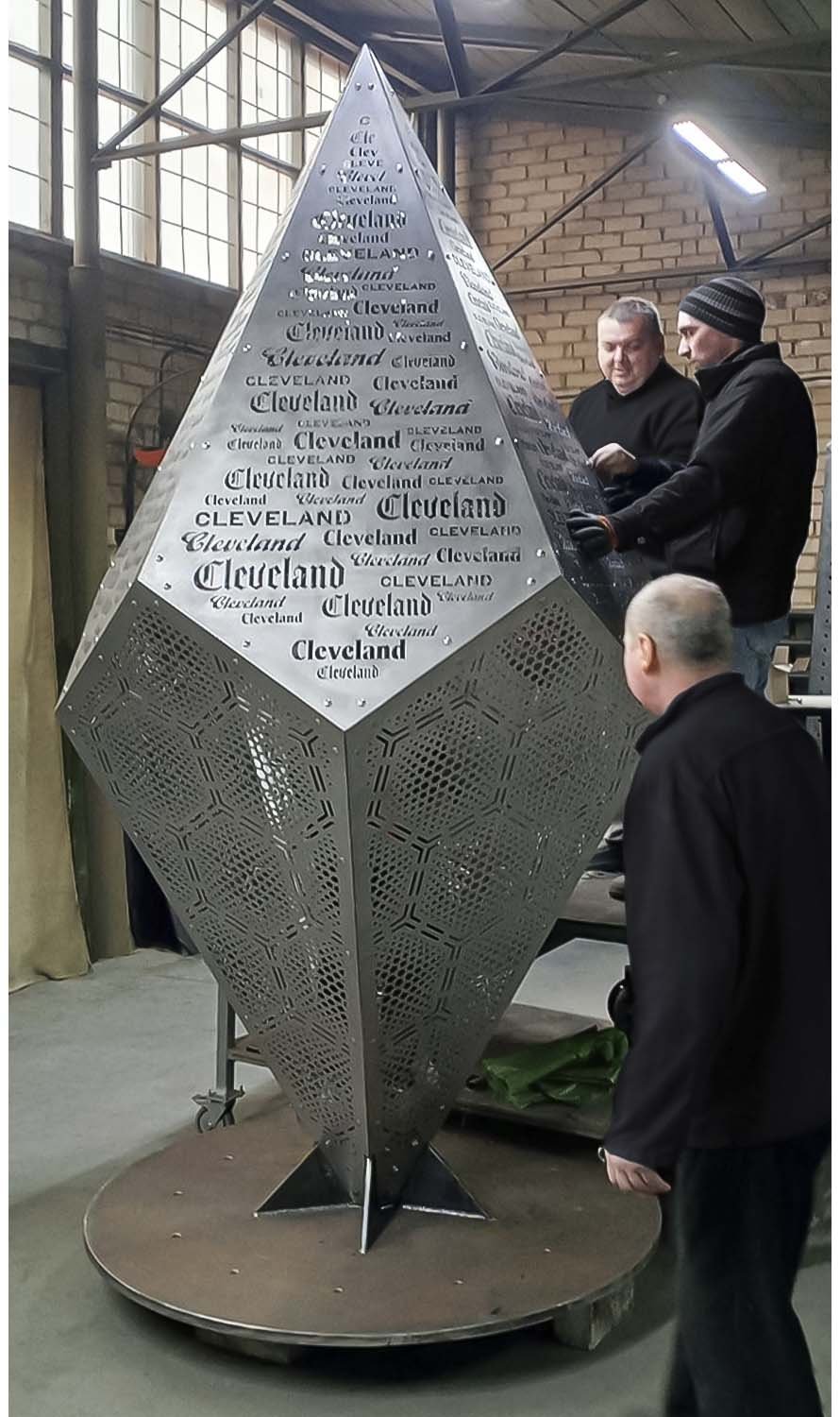 Skyform Studio employees assemble the metal art installation "Cleveland" at the factory.