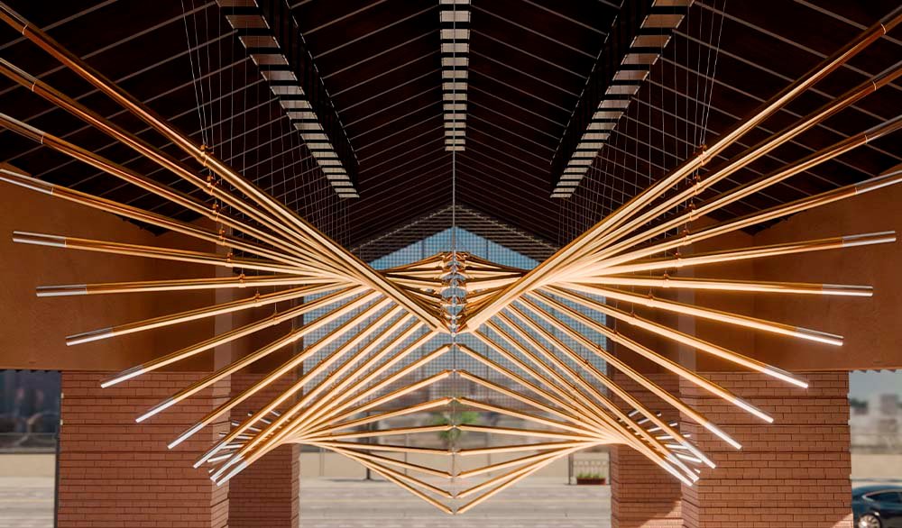 Kinetic installation "Wings of the Valley" made of suspended gold tubes under the roof of the public space