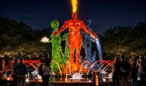The “Four Elements” light-and-music installation is a large-scale composition of four illuminated figures symbolizing fire, water, earth, and air. The central fire figure, crowned with a flame above its head, is surrounded by dynamic water arches and illuminated lotuses, creating a striking evening focal point in the city park.